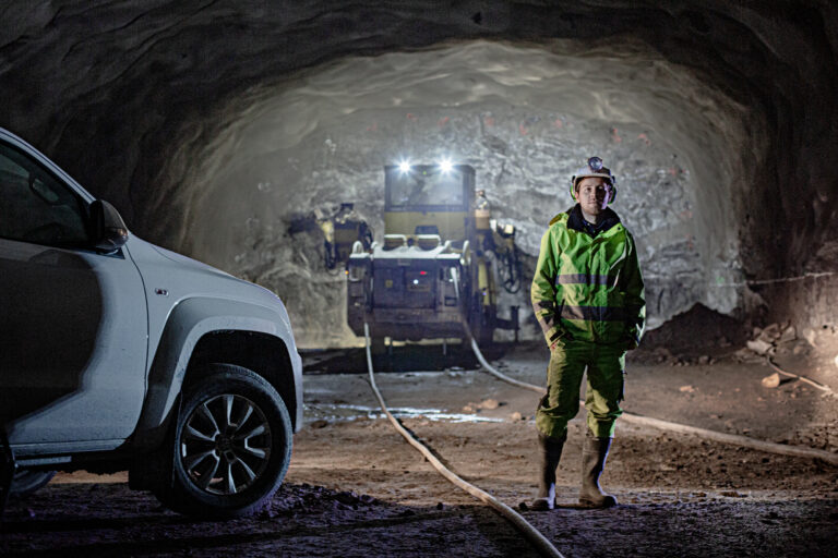 Thomas från Subterra står i tunneln förbifart stockholm framför en Epiroc Boomer