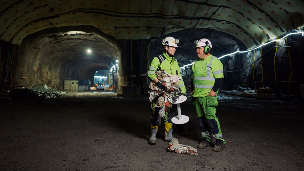 Två personer i arbetsläder i arbetstunneln vid tunnebanebygget.